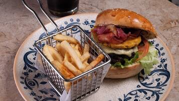 A plate with a burger and fries, a glass of iced drink, and a decorative plate.
