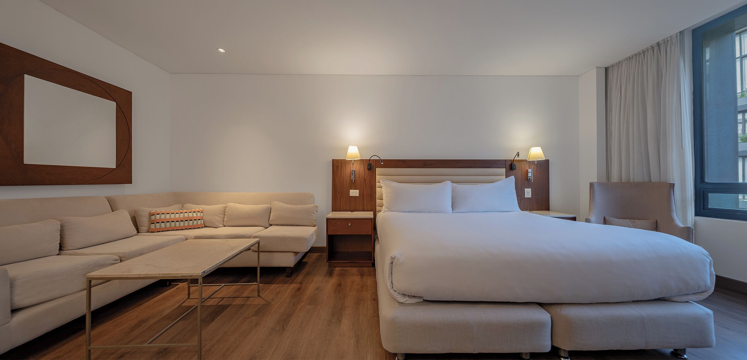 Ein modernes Hotelzimmer mit einem großen Bett, einer Couch, einem kleinen Tisch und einem Sessel.