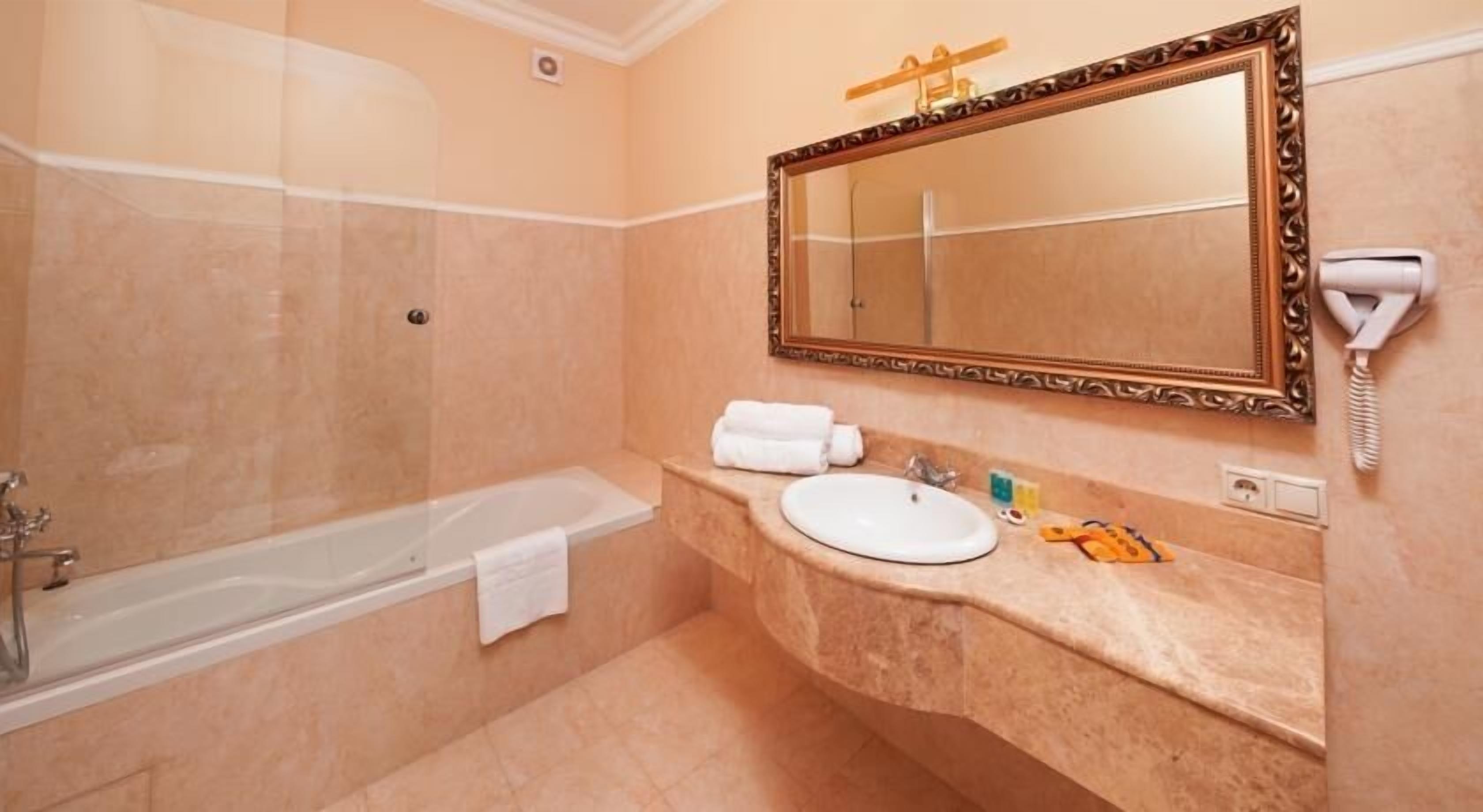 A bathroom with a bathtub, a sink, a mirror, and a telephone.