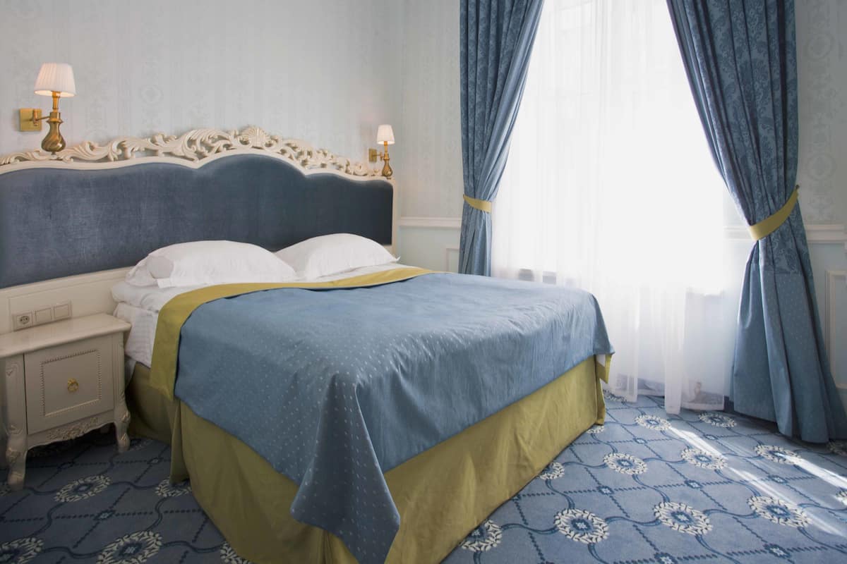 A neatly made bed with a blue and yellow bedspread, a white pillow, and a matching nightstand.