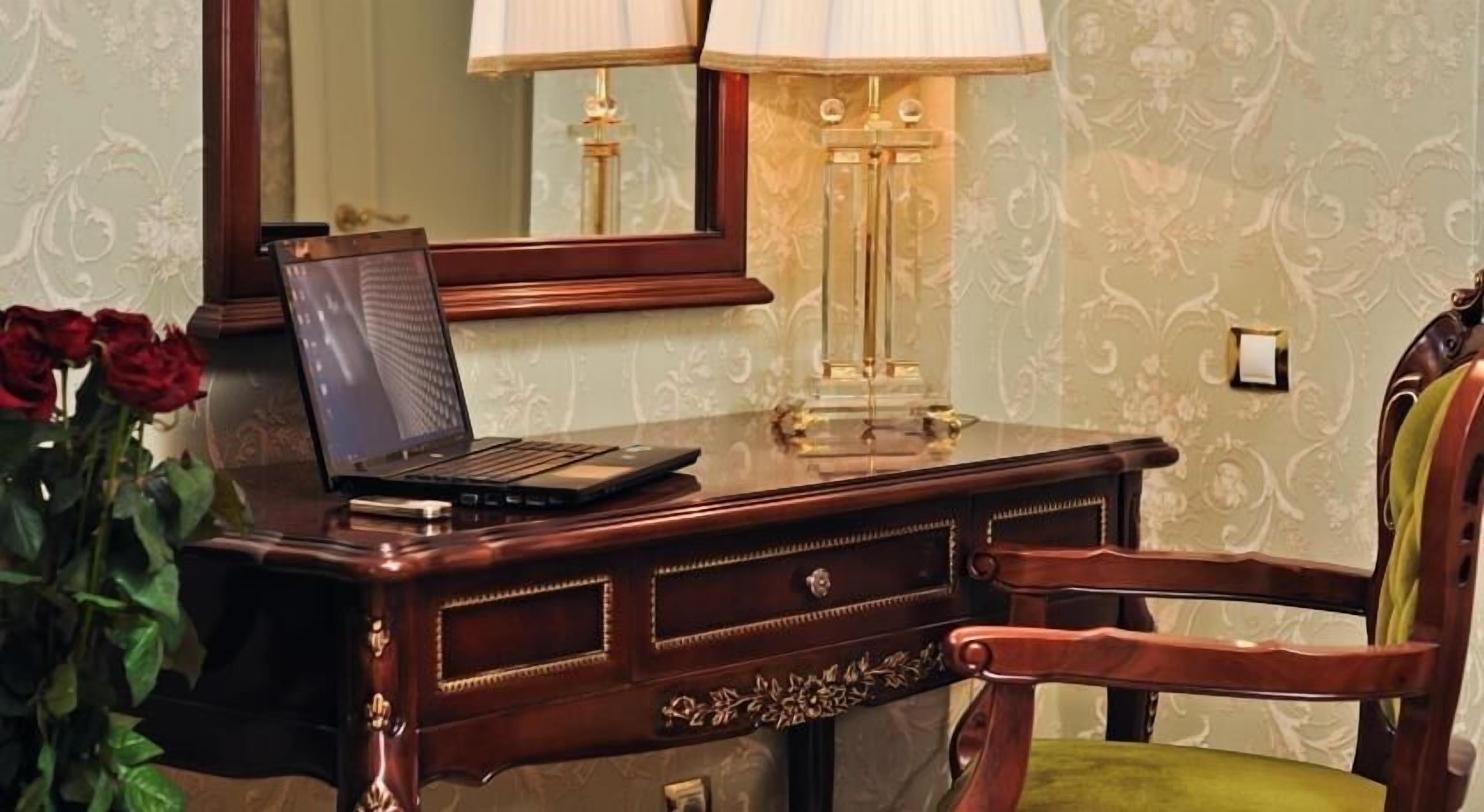 A wooden desk with a laptop, a lamp, and a chair.