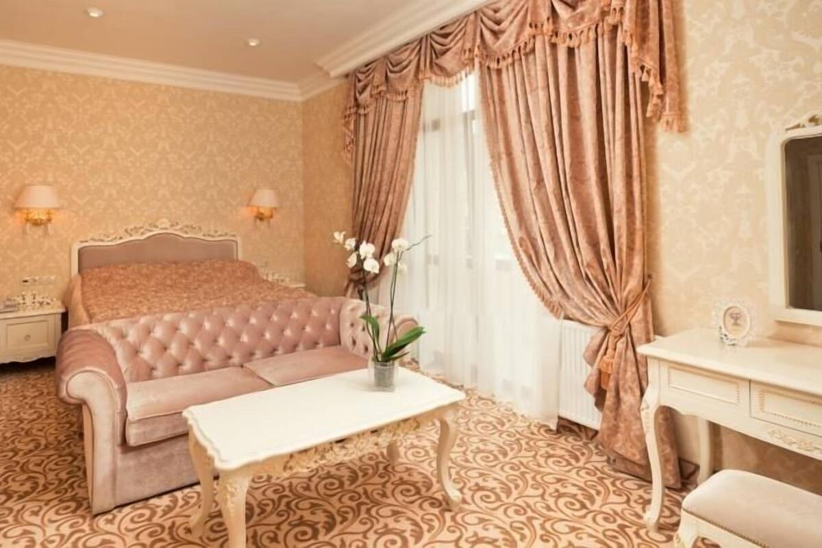 A bedroom with a tufted sofa, a bedside table, a dresser, and a mirror.
