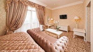 Habitación de hotel con una cama grande, un área de descanso, un escritorio y televisión.