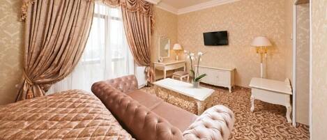 Habitación de hotel con una cama grande, un área de descanso, un escritorio y televisión.