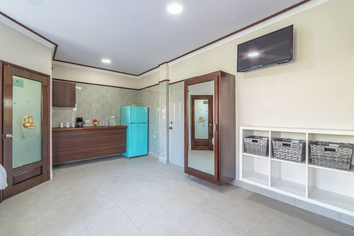 A modern kitchen with a blue refrigerator, wooden cabinets, and a built-in TV.