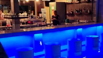 Zona de bar con mostrador iluminado en azul y taburetes.