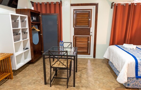 Una habitación de hotel con cama, escritorio con silla, armario y televisión.