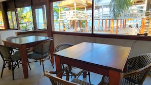 A restaurant with a view of a resort. Tables and chairs are arranged for dining.