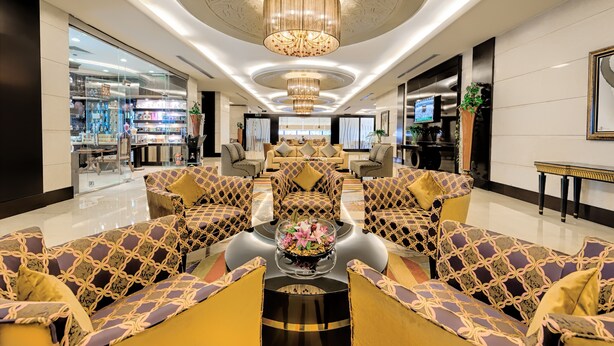 A spacious lobby with a central seating area, a chandelier, and a large window.