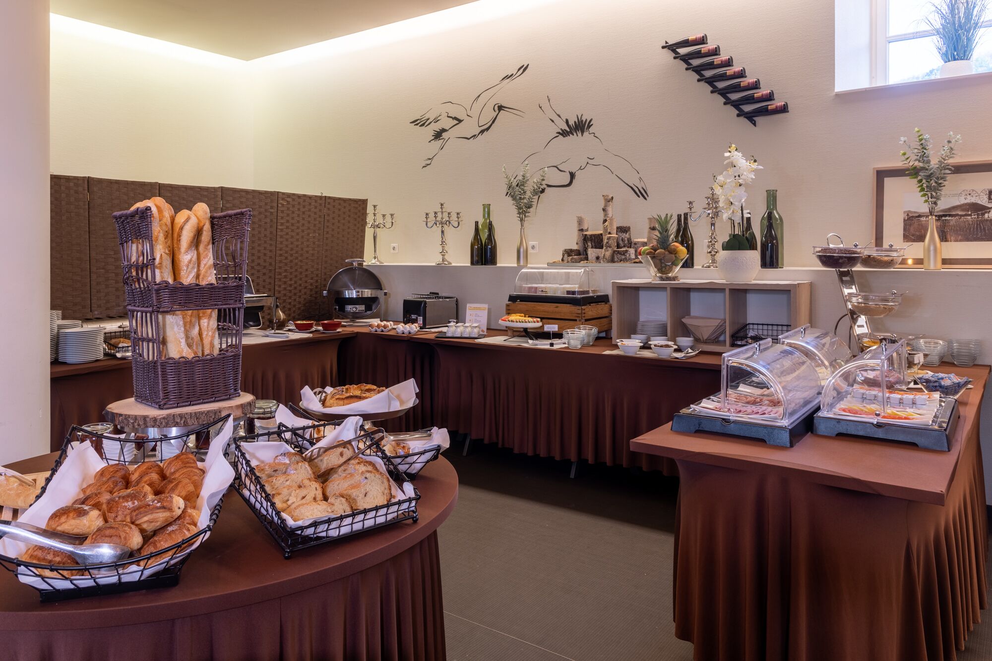 A buffet setup with various food items and a wine rack on the wall.