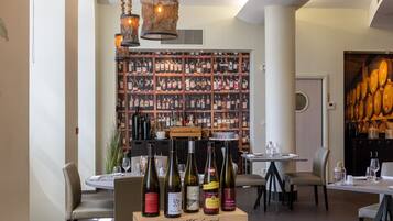 Un restaurante con una vitrina de vinos, luces colgantes y una mesa con botellas de vino.