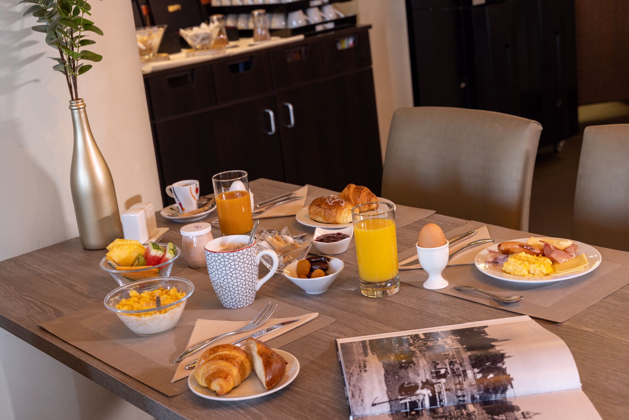 A breakfast table with croissants, eggs, and orange juice.