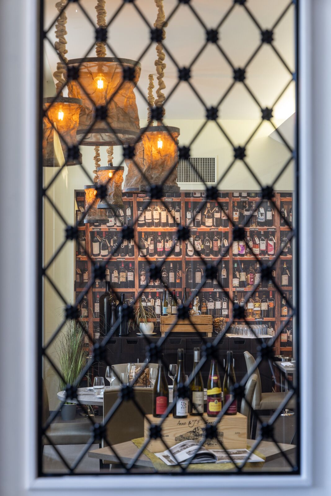 Eine Bar mit Weinkühler, Flaschen und einer Hängelampe.
