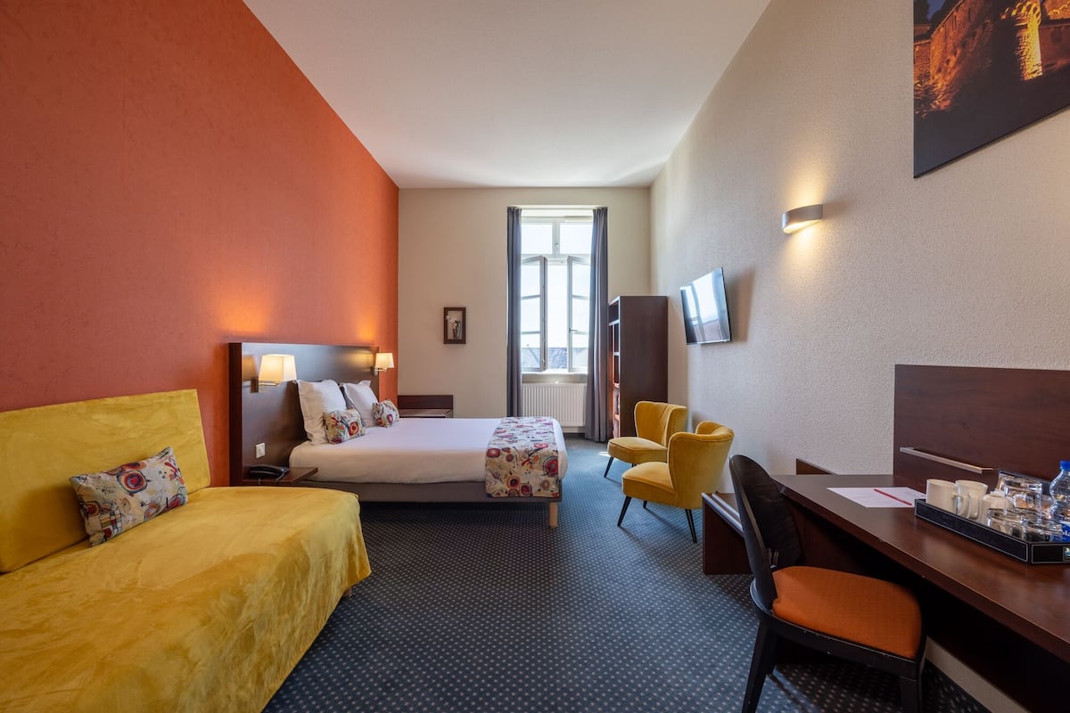 Ein Hotelzimmer mit Bett, Schreibtisch, Stuhl, Fernseher und Fenster.