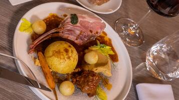 A plate of food with a lamb shank, potatoes, and a sauce.