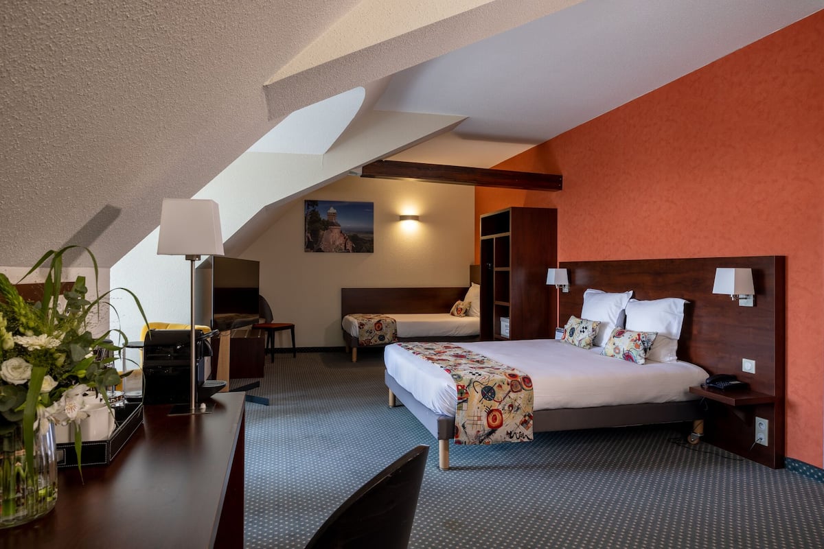Ein Hotelzimmer mit Bett, Schreibtisch, Stuhl, Lampe und einem Bild an der Wand.