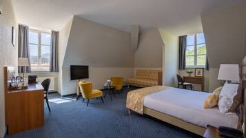 Habitación de hotel con una cama grande, un escritorio, una silla, un televisor y una ventana con cortinas.