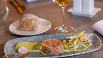A dining table with a plate of food, a glass of wine, and a fork.