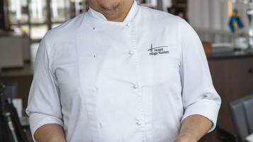 A chef in a white uniform holding two plates of food.