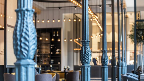 Un interior moderno con elegantes columnas azules, iluminación ambiental y un rincón de estar acogedor.