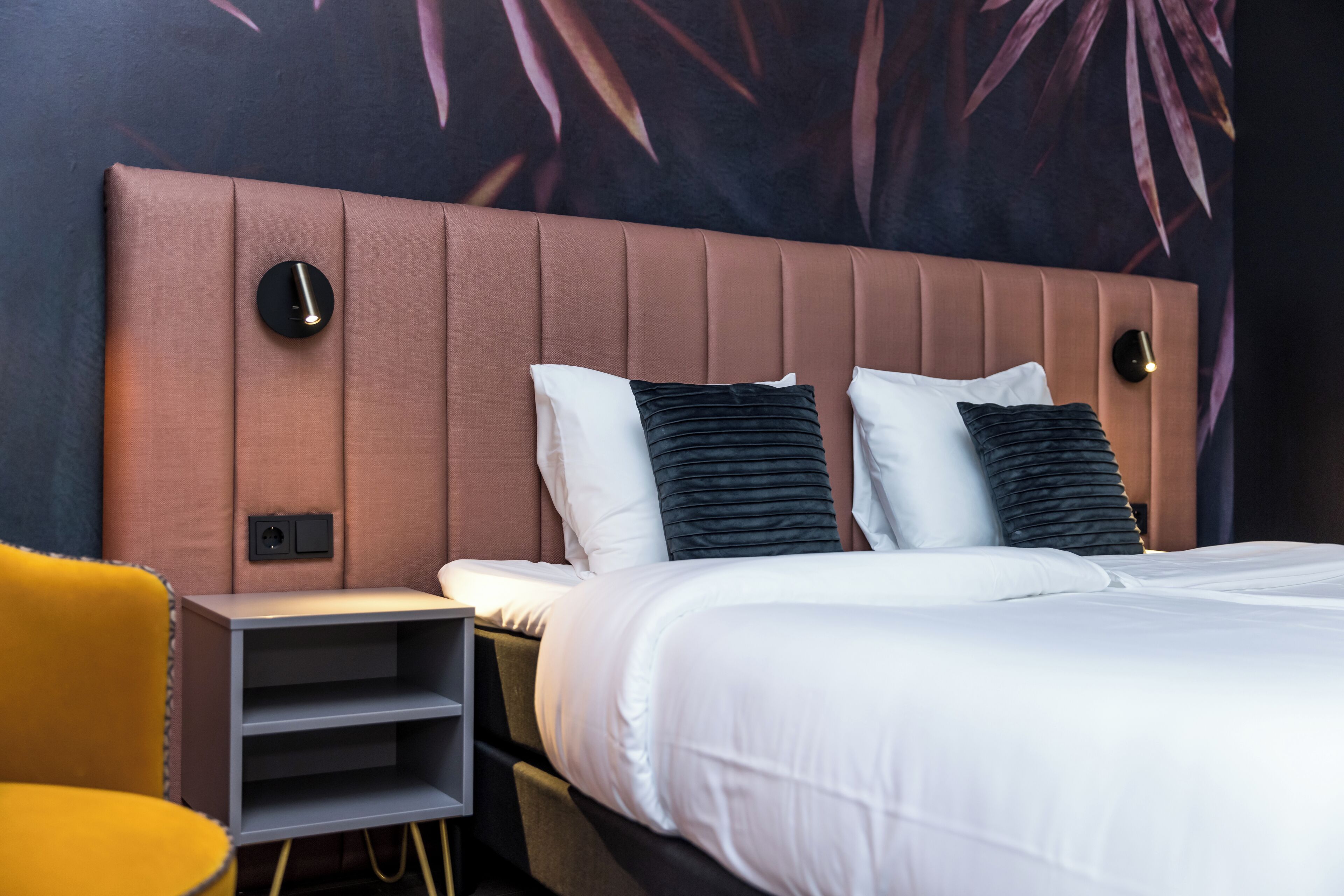 Ein modernes Hotelzimmer mit einem großen Bett, einem Nachttisch und einem gelben Sessel.