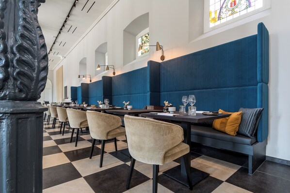 Un restaurante con piso a cuadros, asientos tapizados en azul y mantel a cuadros.