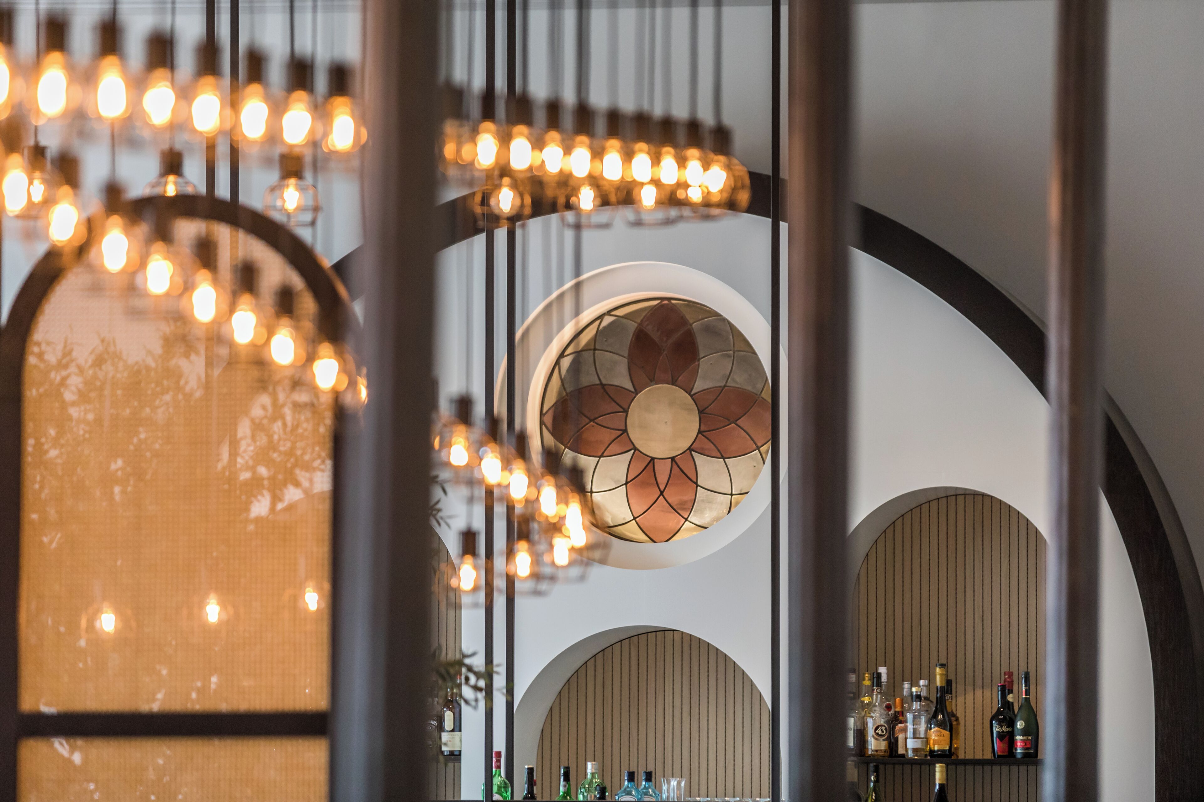 A bar area with hanging lights and a circular stained glass window.