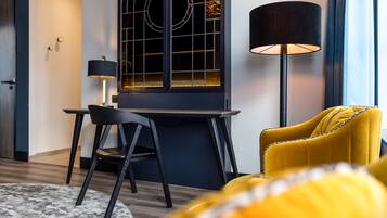 Een moderne kamer met een bureau, stoel en een gele fauteuil.
