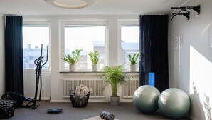 Una sala de estar moderna con un ventanal grande, equipo de ejercicio y vista a la ciudad.