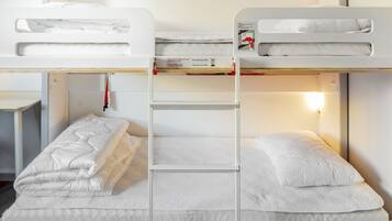 Una cama litera con escalera, ropa de cama blanca y una mesita.