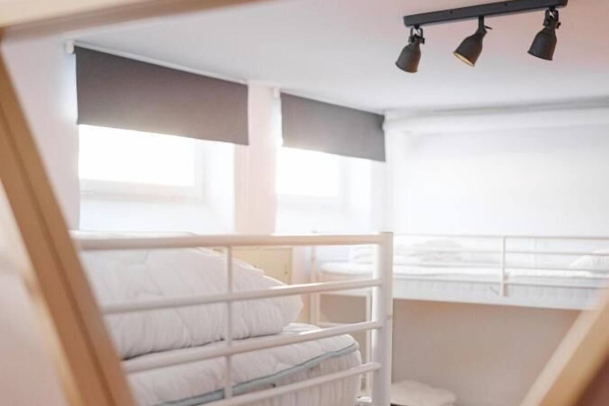 Ein Schlafsaalzimmer mit Etagenbetten, einem Schreibtisch und einem Stuhl.