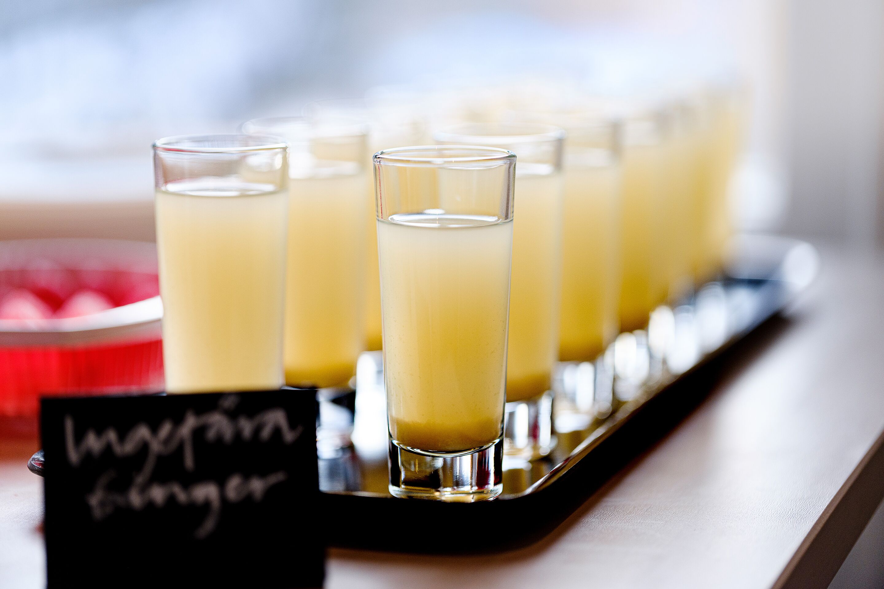 A tray with several glasses of a yellow beverage, possibly a smoothie or juice, with a sign that reads "Lager Bier."