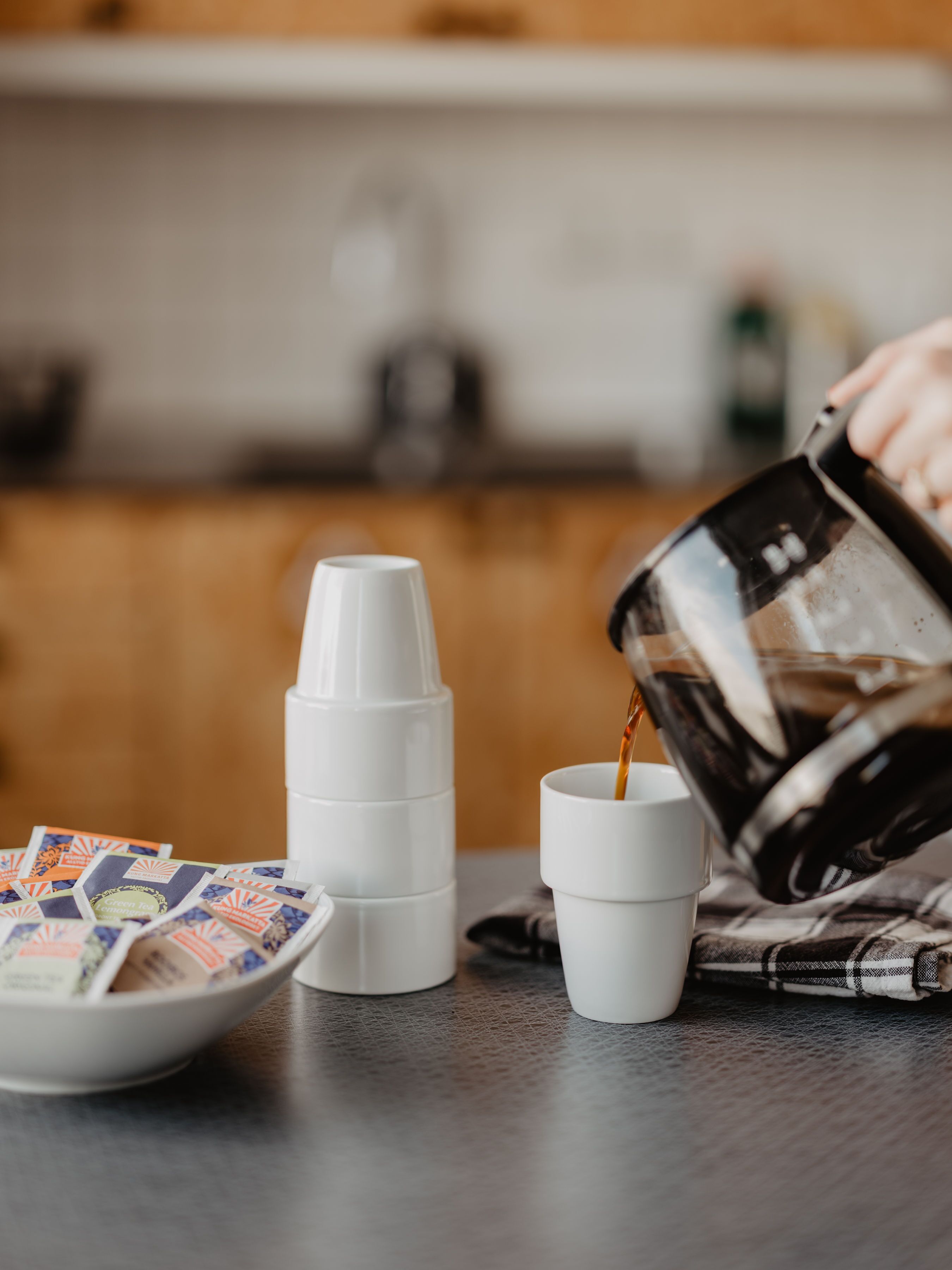 A coffee-making setup with a coffee maker, cups, and coffee pods on a kitchen counter.
