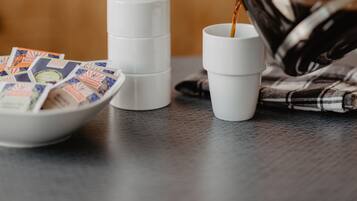 A coffee-making setup with a coffee maker, cups, and coffee pods on a kitchen counter.