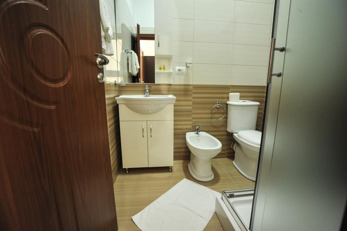Une salle de bain avec une porte en bois, un lavabo, un bidet et des toilettes.