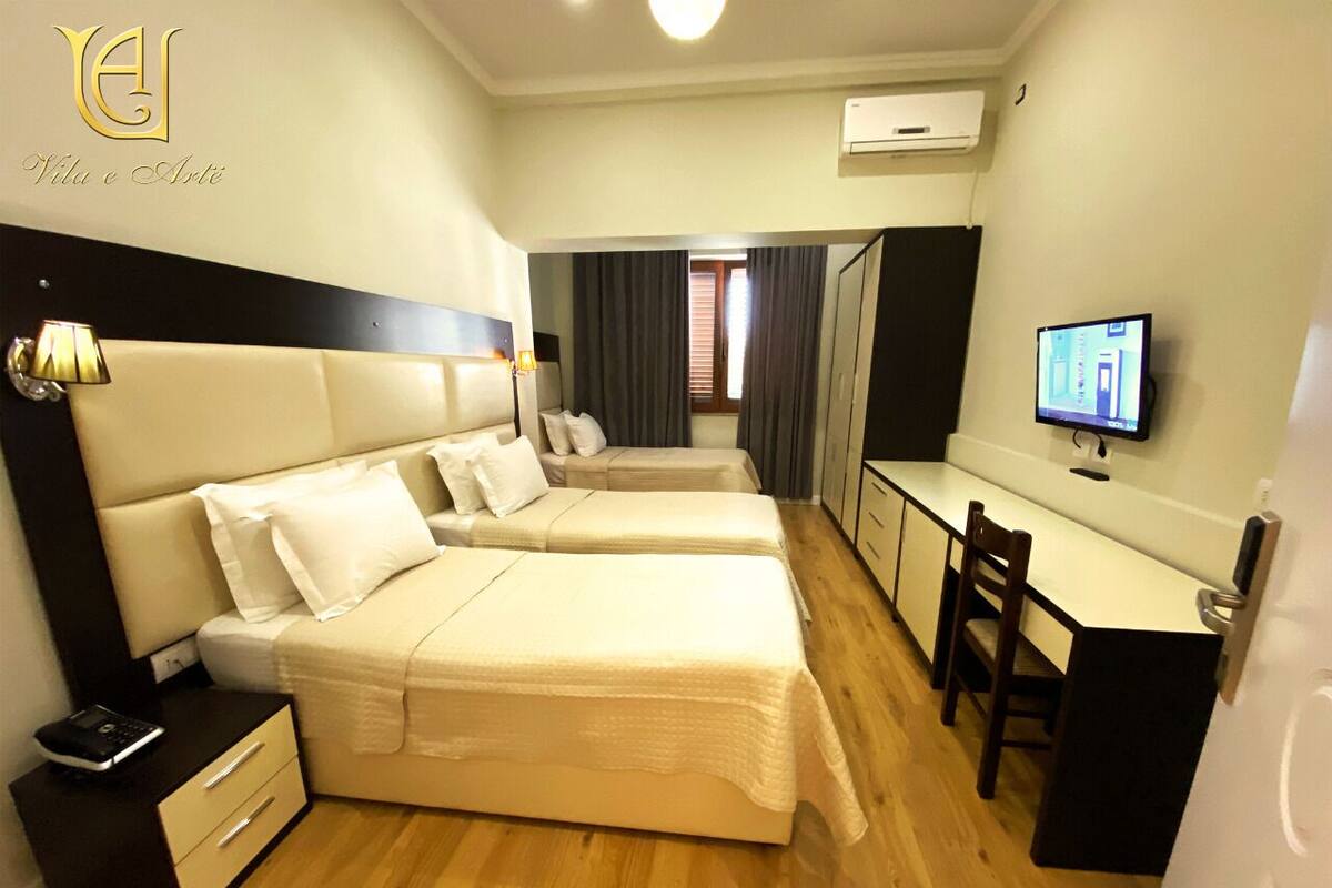 Una habitación de hotel con dos camas, un escritorio, una silla, un televisor y un armario.