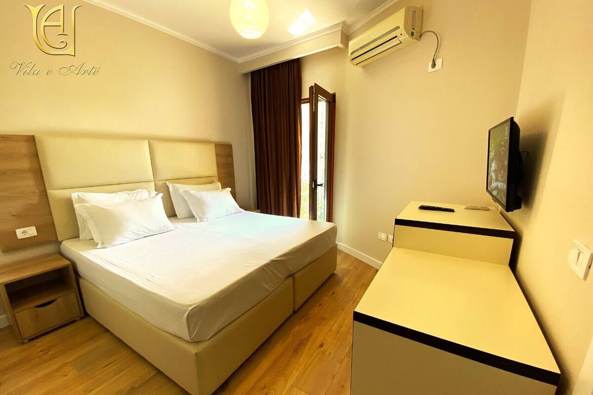 Una habitación de hotel con cama, mesita de noche y un escritorio pequeño con silla.