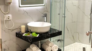 Un baño con ducha de vidrio, un lavamanos blanco y un salpicadero de mármol.