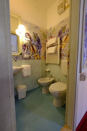 Kylpyhuone, jossa on pesuallas, kaksi wc:tä, bidee ja peili.