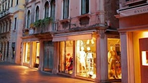 A historic building with arched windows and a boutique store with mannequins. - Ca' Pedrocchi (Venice)