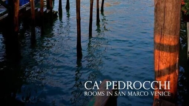 A canal with wooden posts, boats, and a historic building with domes in Venice. - Ca' Pedrocchi (Venice)