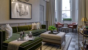 Ein Wohnzimmer mit einem grünen Sofa, einem Couchtisch mit Tablett, einem gerahmten Kunstwerk und einer Chandelieber.