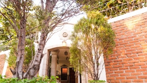 A building entrance with a brick wall, a stone archway, and a staircase leading to the door. - Hotel El Almendro (Managua)