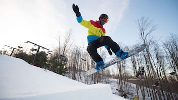 A snowboarder performing a jump on a snowy slope with trees in the background.