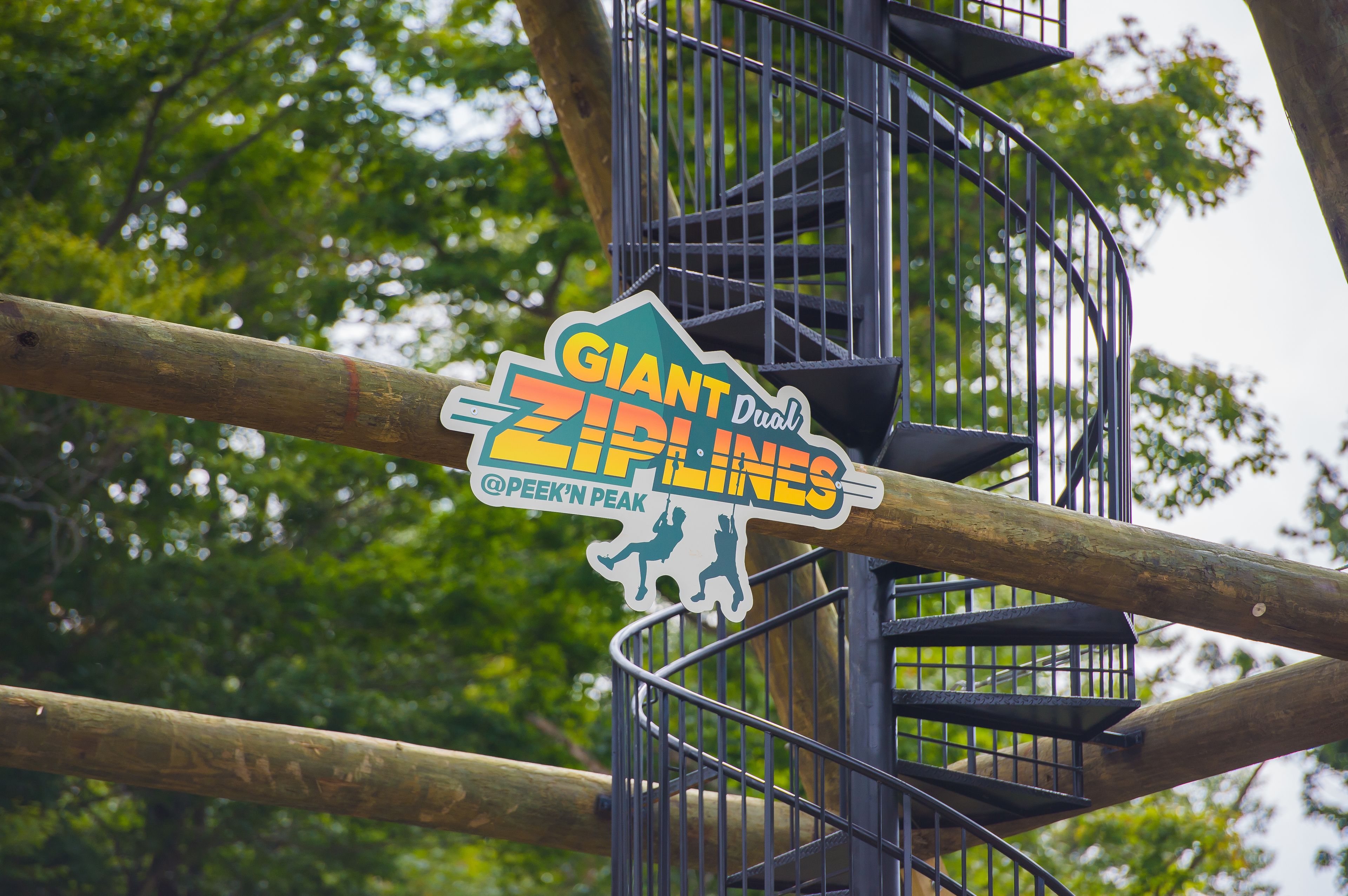 A sign for "Giant Dual ZipLines" with a metal staircase structure.