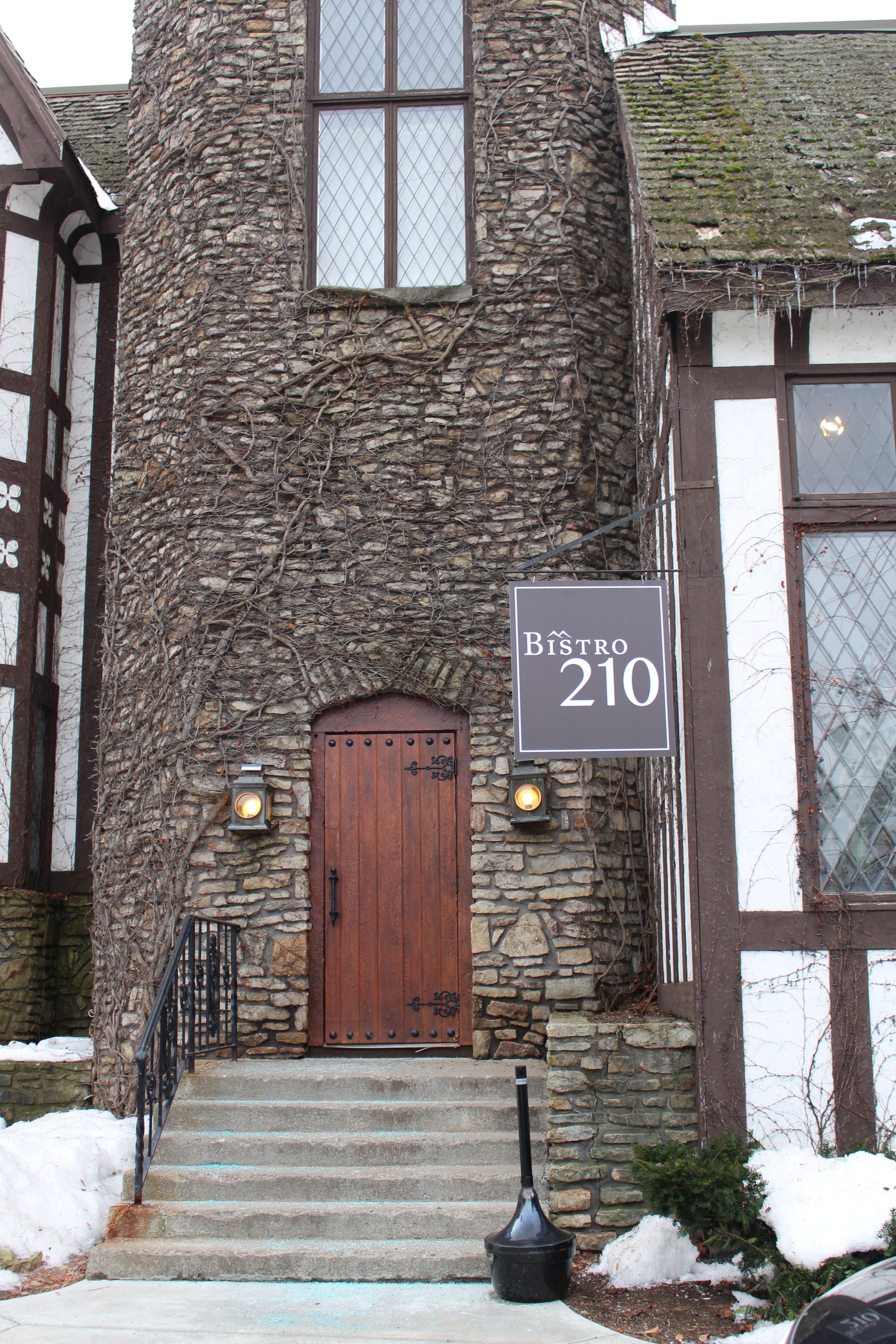 Un edificio de piedra con puerta de madera y un letrero que dice "Bistro 210".