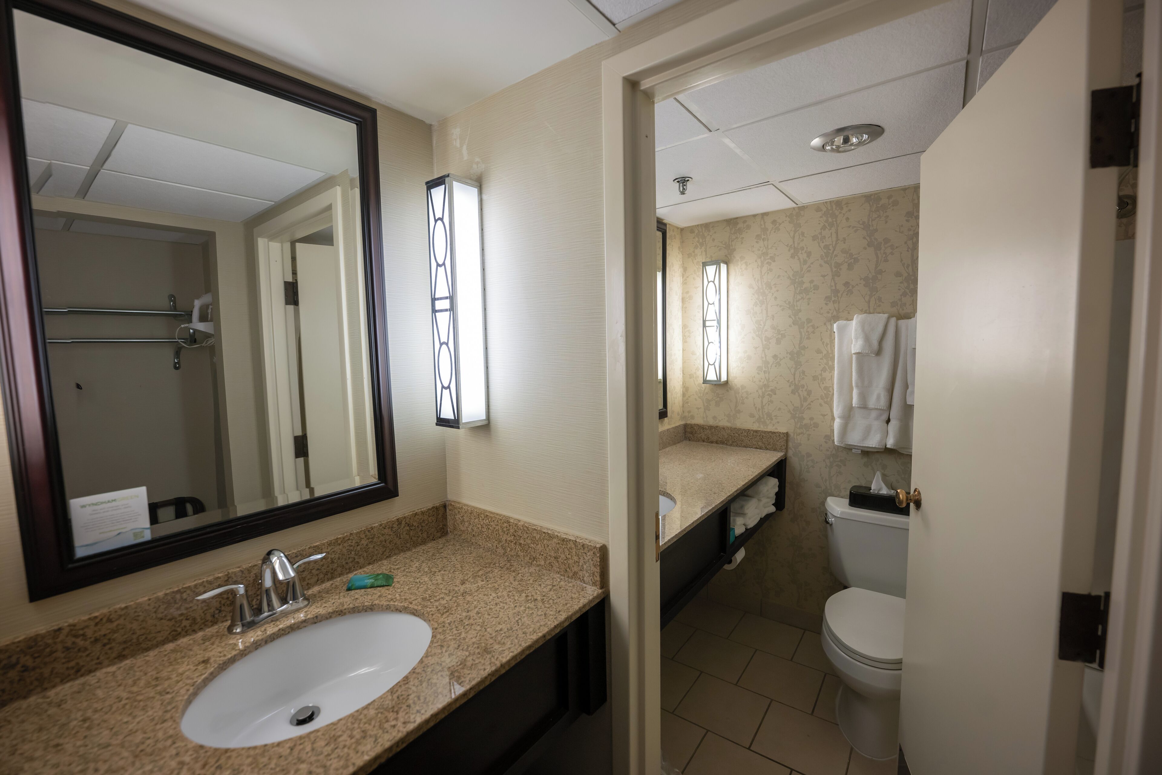 A hotel bathroom with a sink, mirror, and toilet.