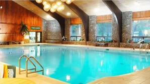 An indoor swimming pool with stone walls, a fitness center, and a view of the outdoors. - Peek'n Peak Resort Trademark Collection by Wyndham (Clymer)