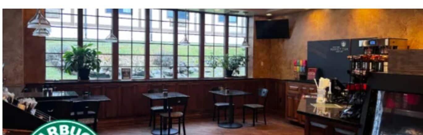 Un restaurante con grandes ventanales, muebles de madera y una zona de bar.