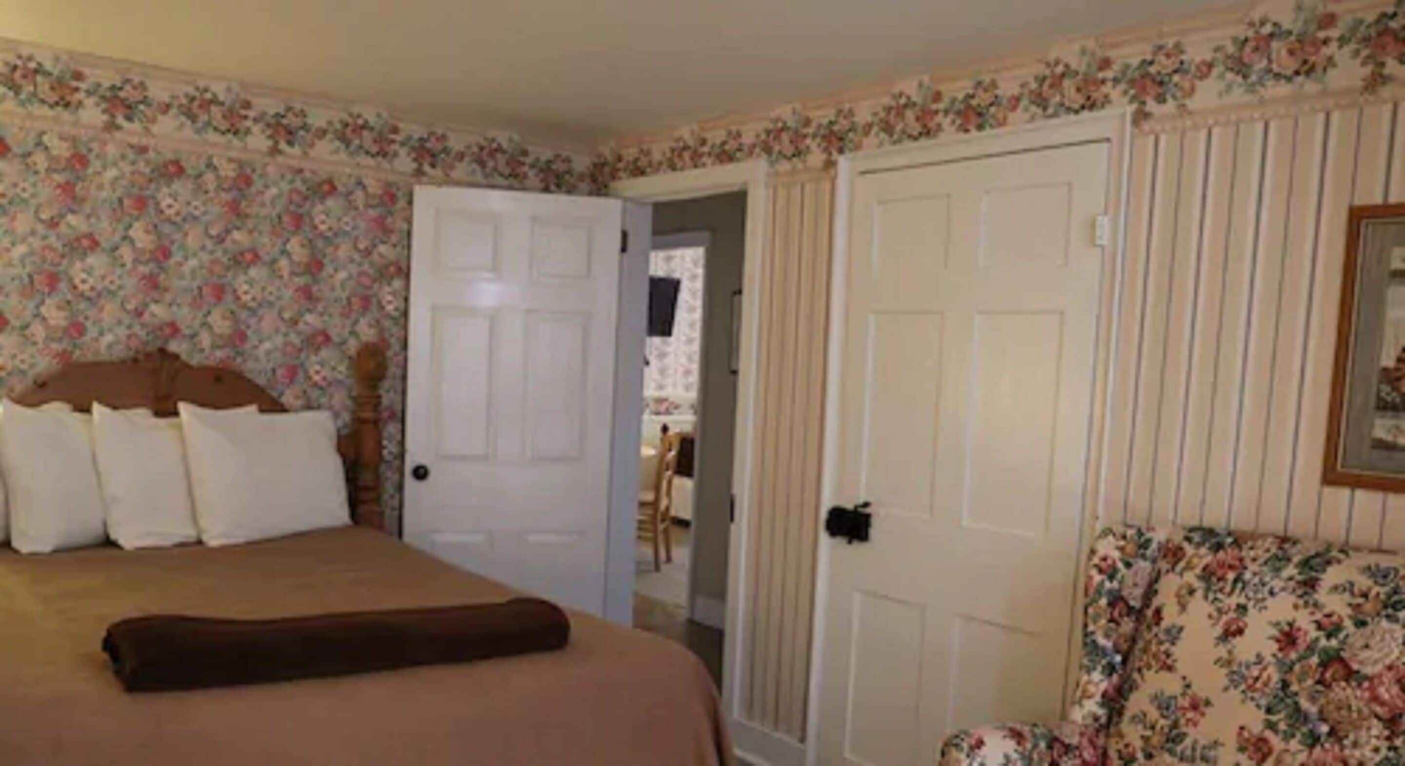 A bedroom with a bed, a chair, and a door leading to another room.